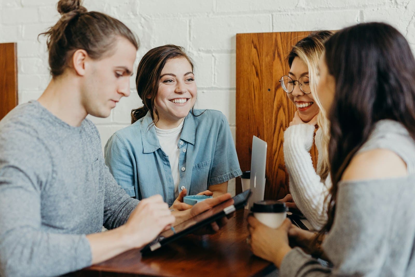 Vier mensen praten ontspannen en lachend met elkaar bij een kop koffie, een warm beeld bij het gesprek dat op een beurs ontstaat
