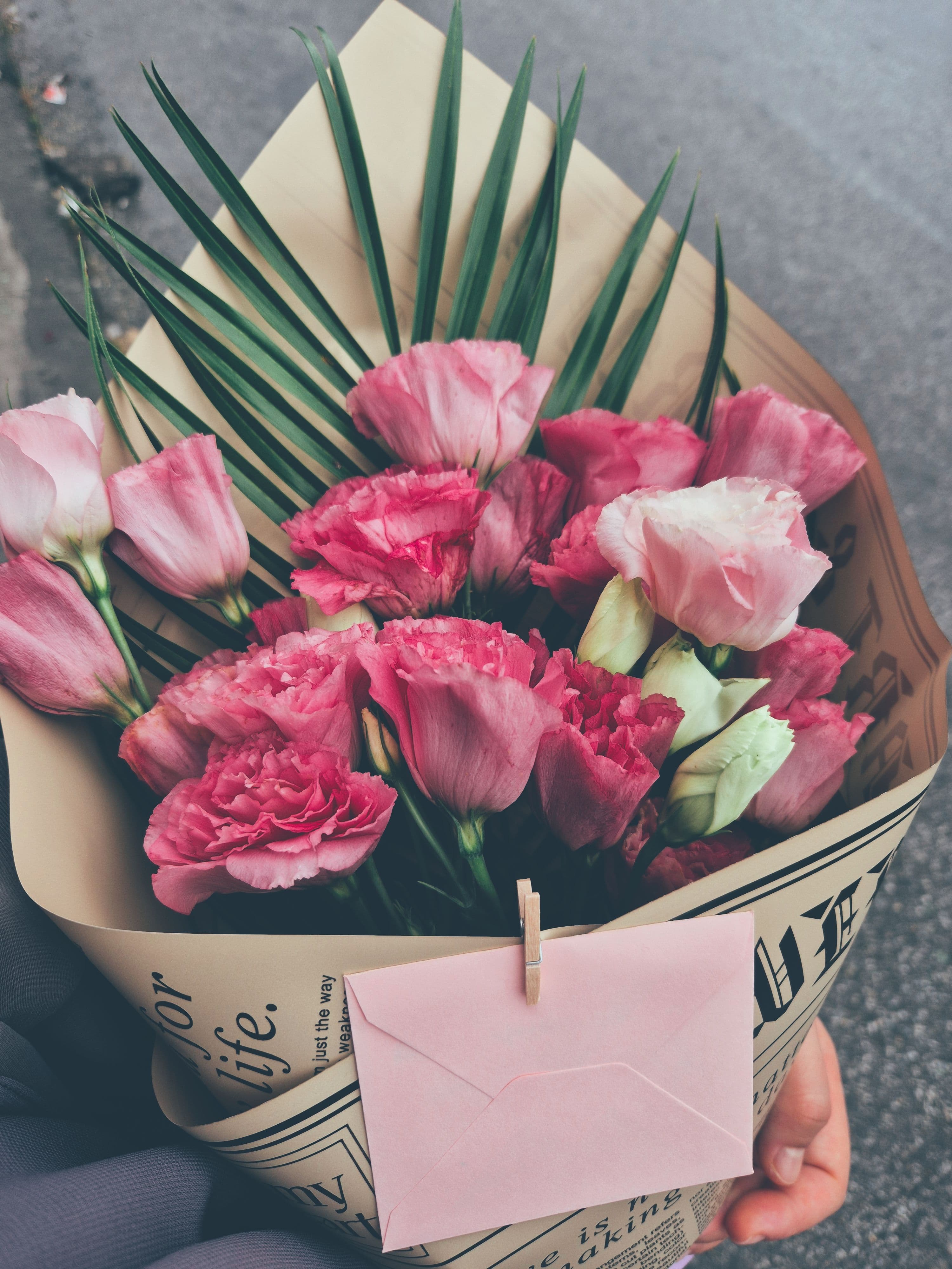Een boeket roze bloemen met een envelop, klaar om als attentie verstuurd te worden, een beeld bij het sturen van een gebaar met een kaartje