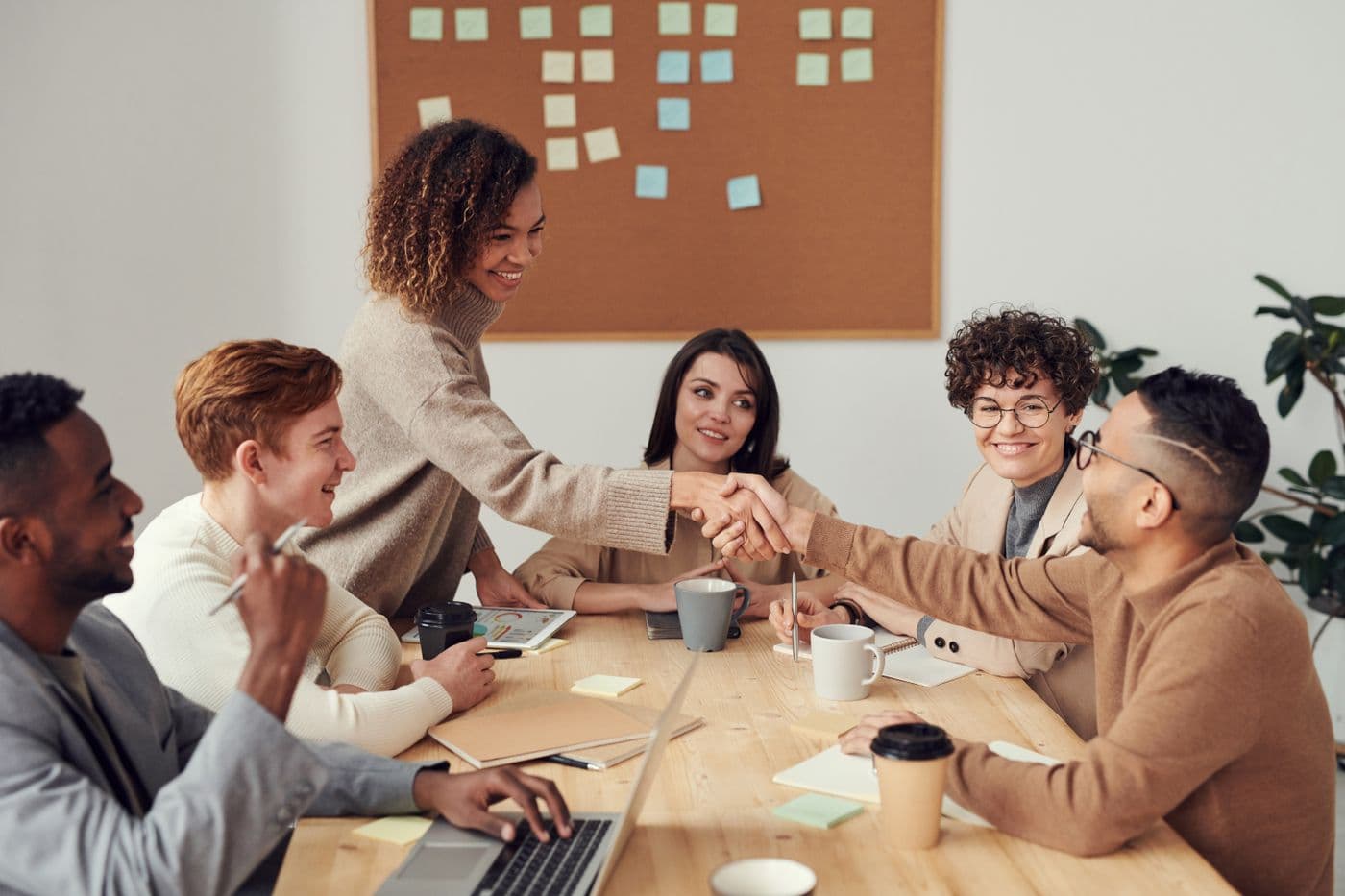 Collega's schudden elkaar de hand aan een vergadertafel met koffie en notities tijdens een zakelijke afspraak over een grote bestelling