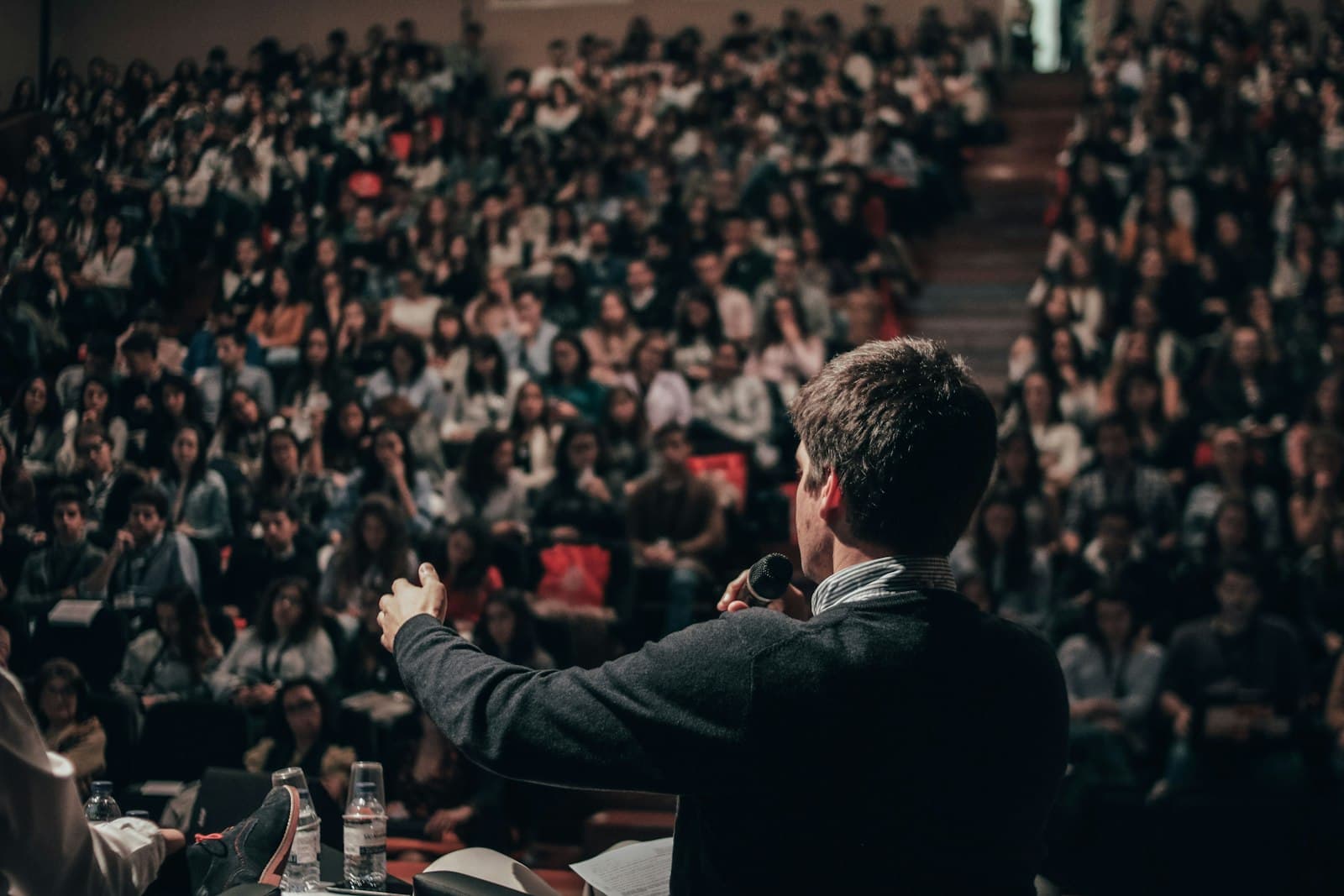 Een spreker staat op het podium voor een volle zaal tijdens een congres, een sfeerbeeld bij koekjes bestellen voor een congres