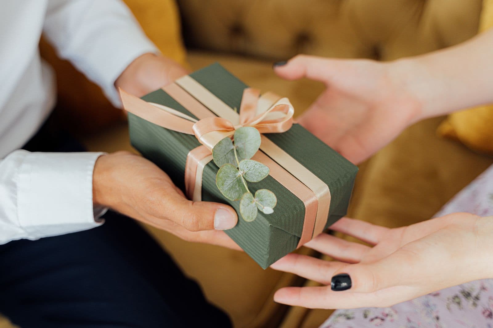 Een zorgvuldig ingepakt cadeau met lint wordt met twee handen overhandigd, een beeld bij het vieren van een dienstjubileum