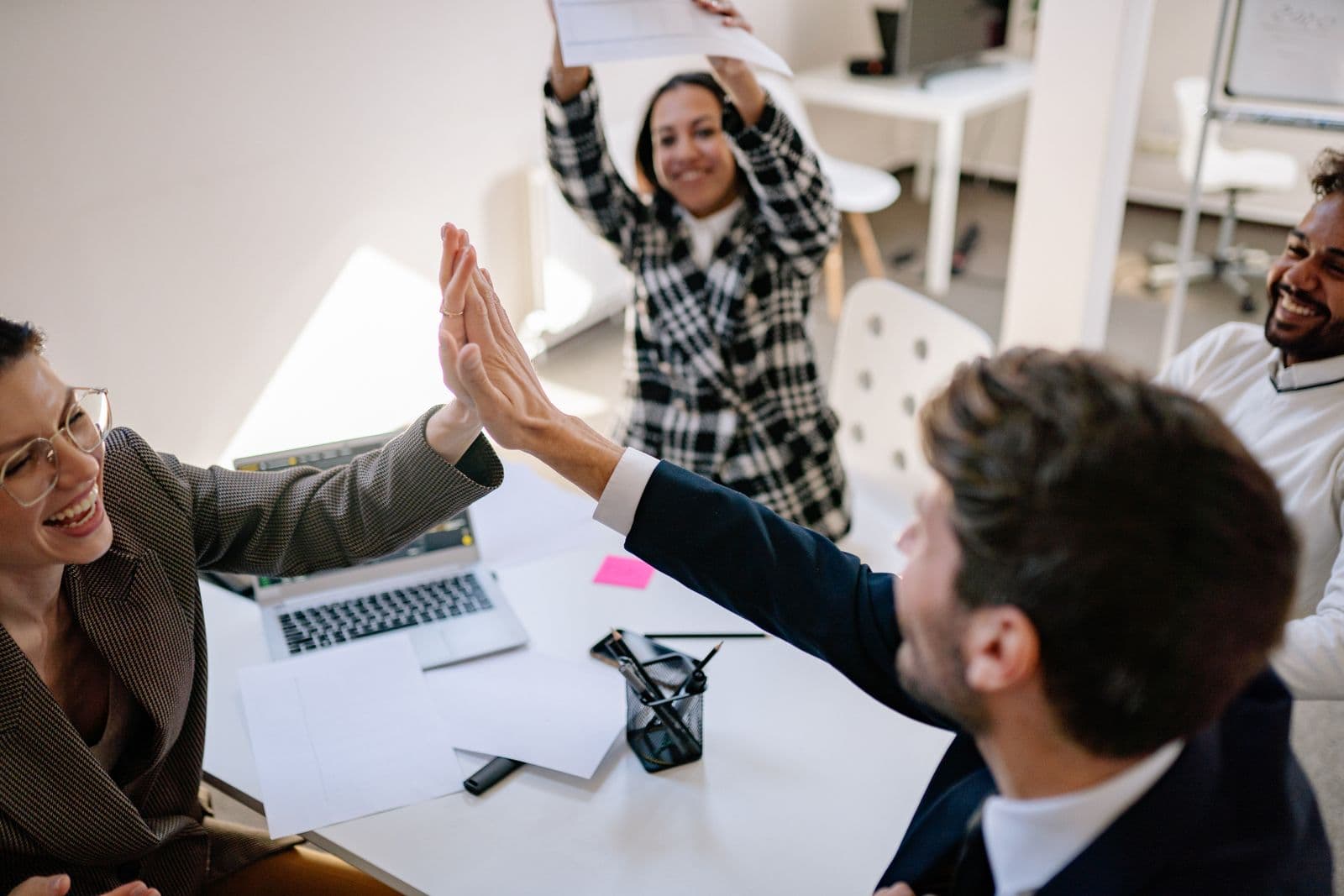 Collega's vieren lachend een succes op kantoor met een high five, een warm beeld bij een dienstjubileum