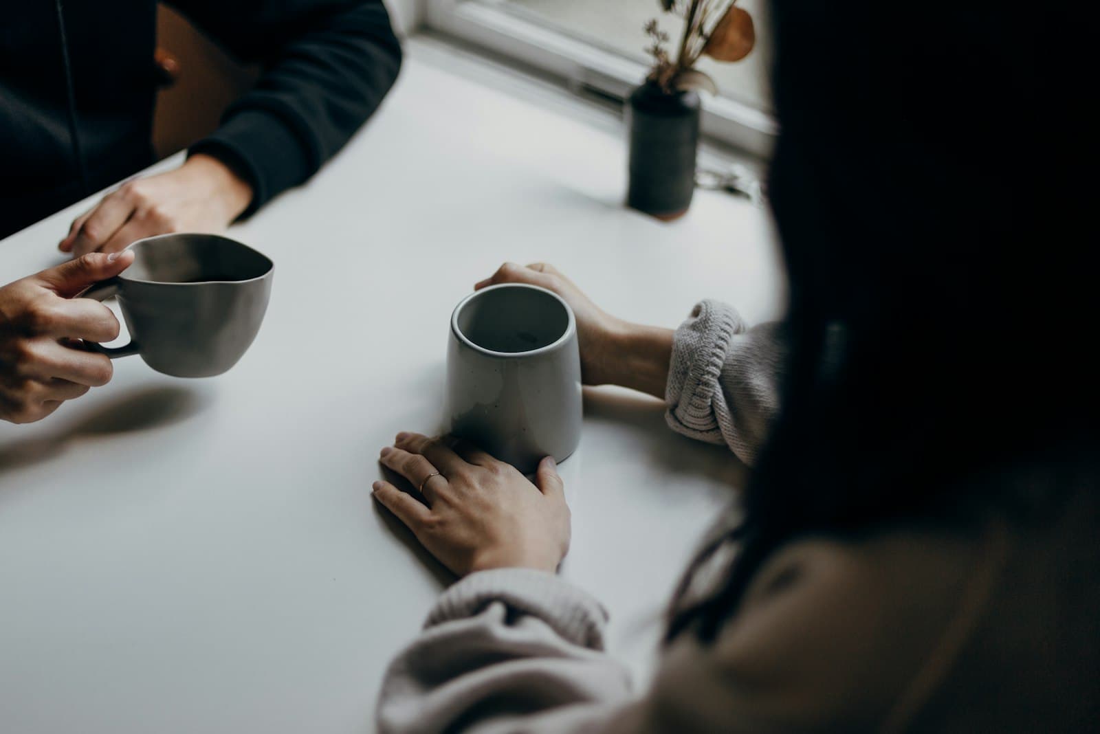 Twee collega's houden een warme mok vast tijdens een koffiepauze, een rustig beeld bij het juiste moment om te trakteren