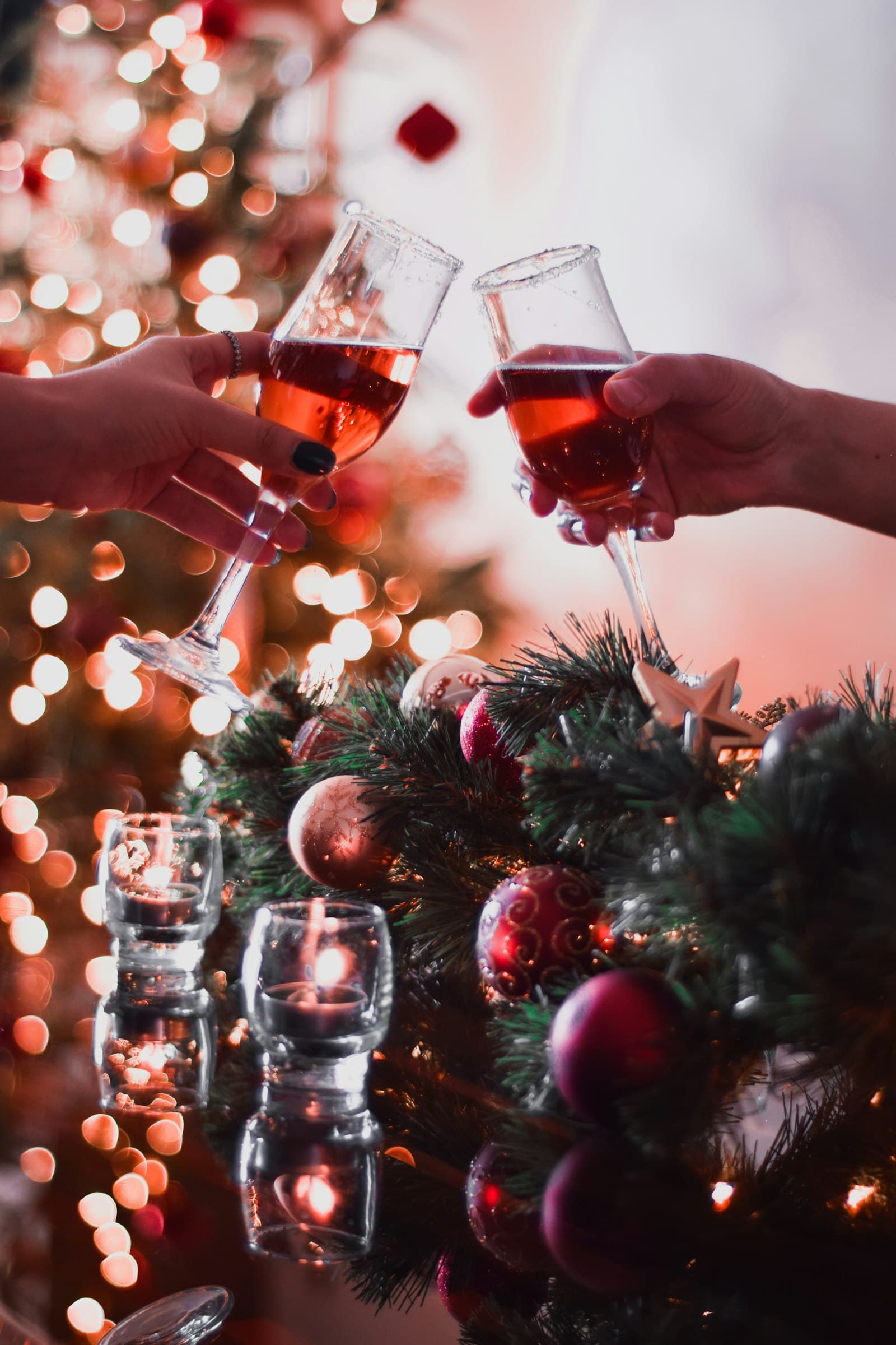 Twee mensen proosten met een glas bij een warm verlichte kerstboom tijdens een kerstborrel