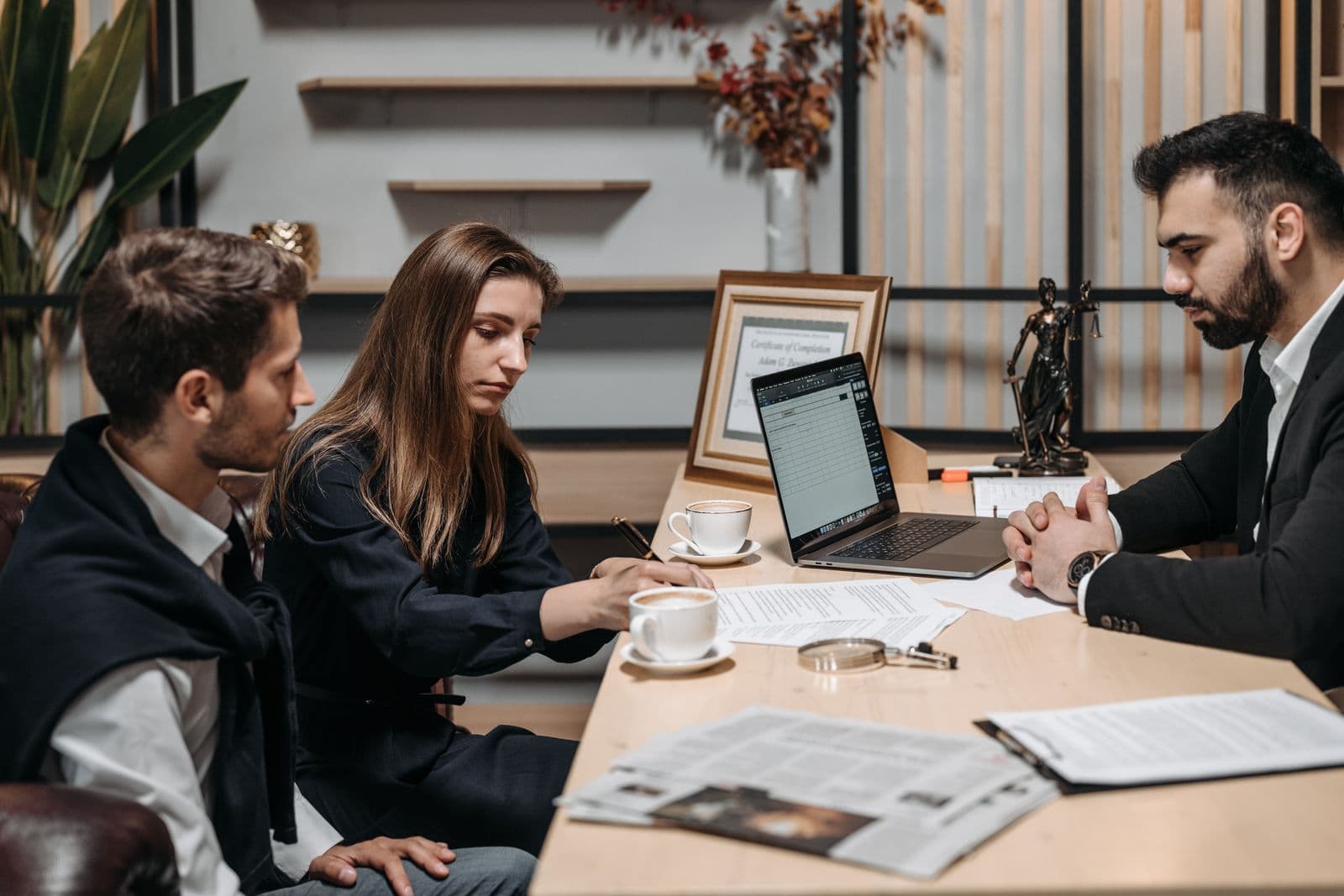 Klant en adviseur overleggen bij koffie op een lichte vergadertafel tijdens een zakelijk bezoek
