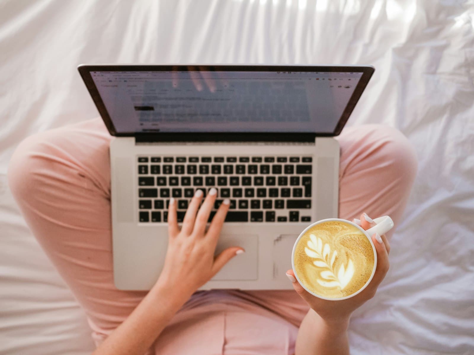 Iemand bestelt thuis ontspannen iets online op een laptop met een kop koffie in de hand, passend bij koekjes online bestellen