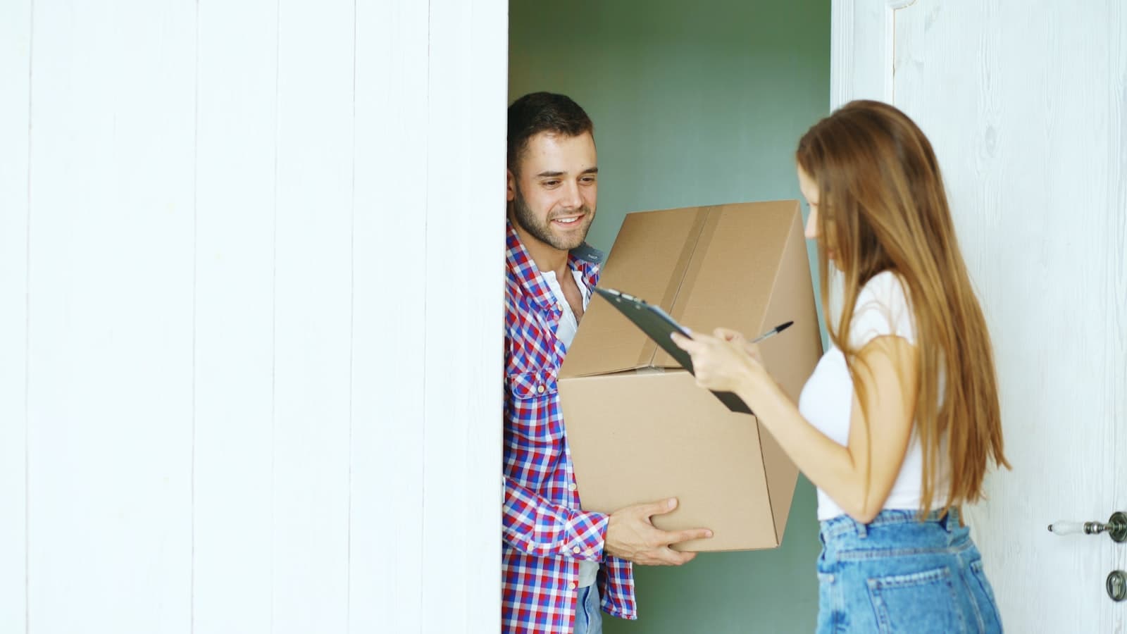 Een bezorger overhandigt lachend een pakketje aan de voordeur aan iemand die tekent voor ontvangst, passend bij koekjes online bestellen en thuis laten bezorgen