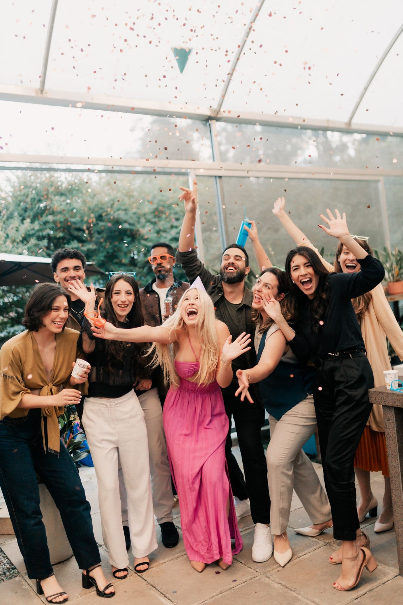 Een grote groep vrienden viert uitbundig met confetti en feesthoedjes tijdens een feest, een beeld van samen genieten