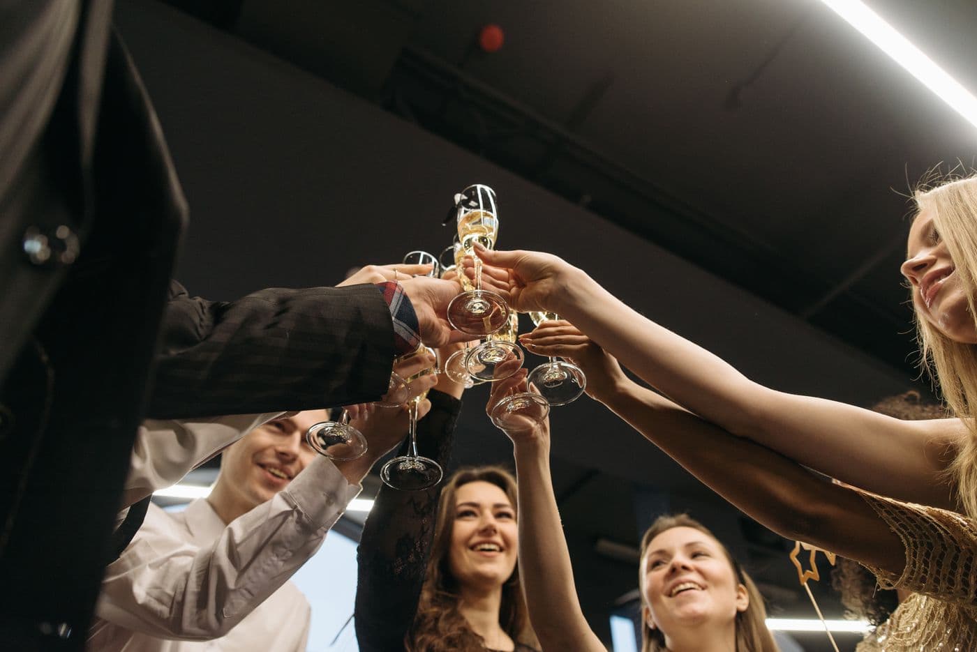 Een groep vrienden proost samen met glazen omhoog tijdens een feestelijk moment, een beeld van vieren zonder gedoe