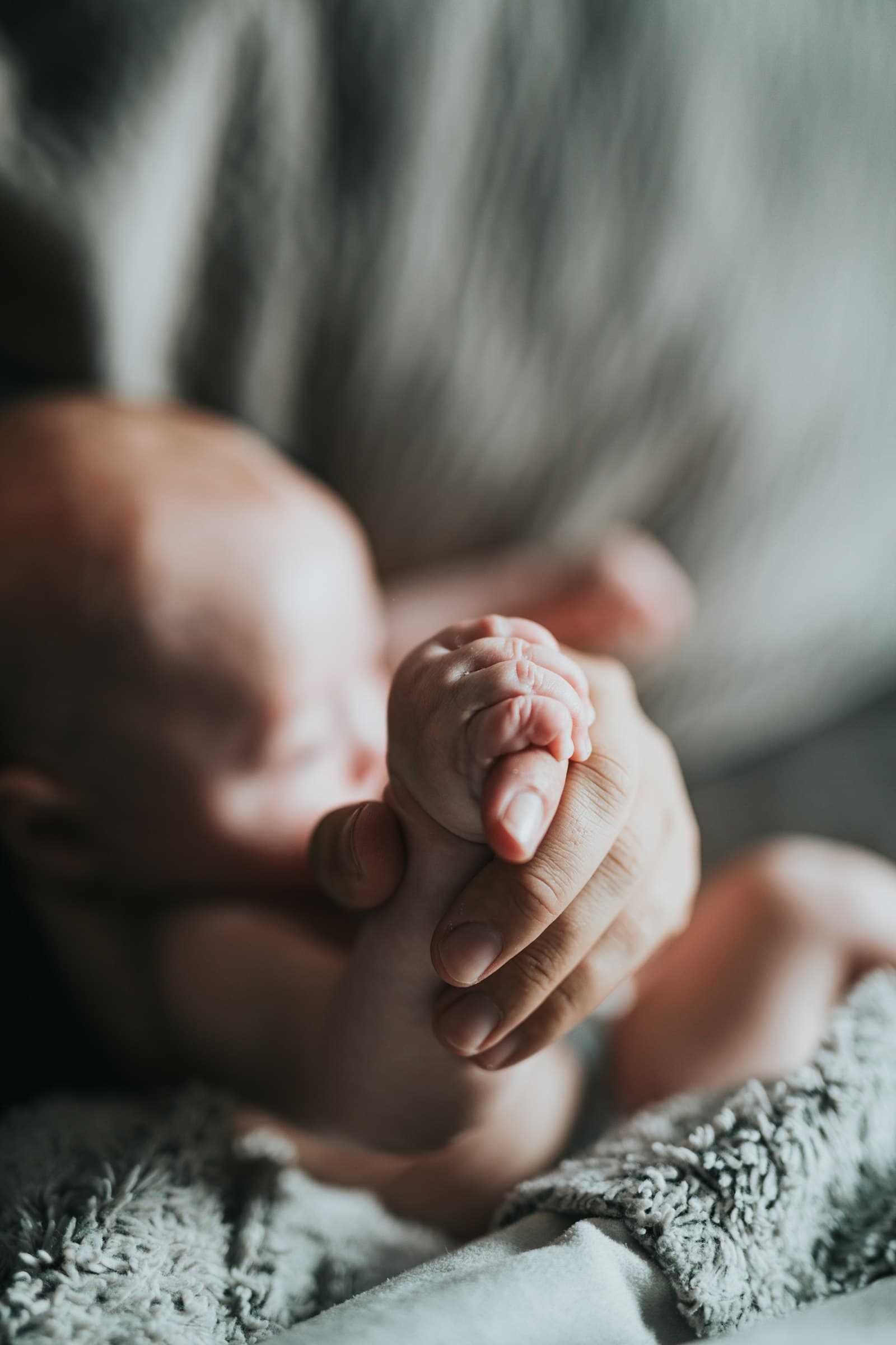 Een pasgeboren baby knijpt met een klein handje om de vinger van een ouder