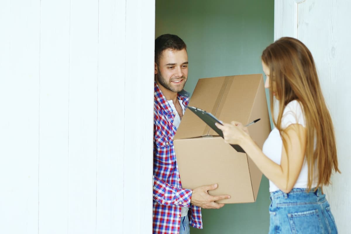Een pakketje wordt aan de voordeur overhandigd en met een glimlach in ontvangst genomen, een beeld bij koekjes als last-minute cadeau laten bezorgen