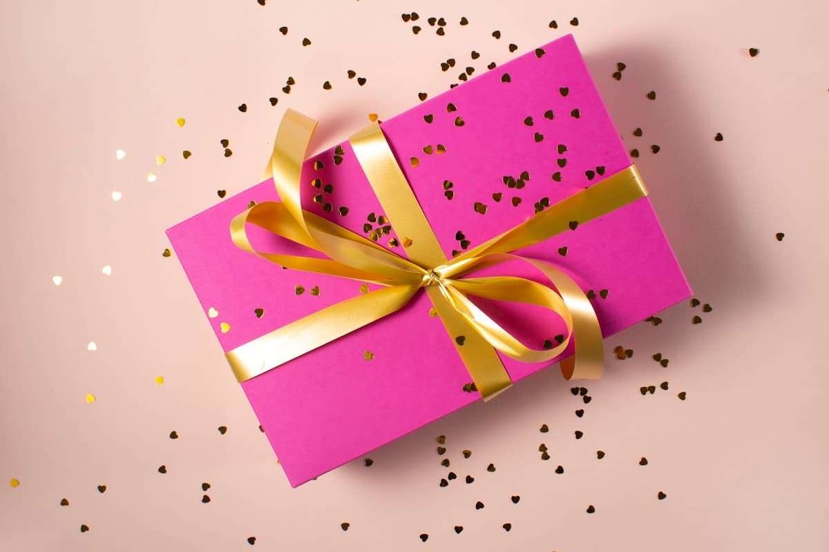 Een feestelijk ingepakt cadeau met goudkleurig lint en confetti, een warm beeld bij koekjes als last-minute cadeau