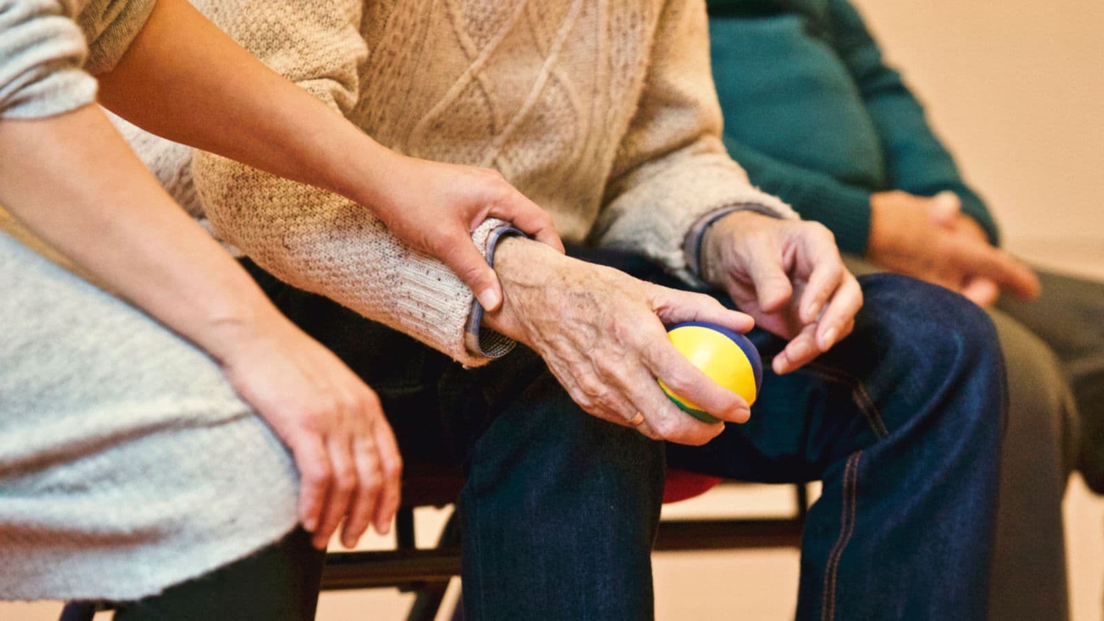 Een jongere hand houdt zacht de hand van een oudere persoon vast als gebaar van zorg, een warm beeld bij koekjes sturen naar een mantelzorger