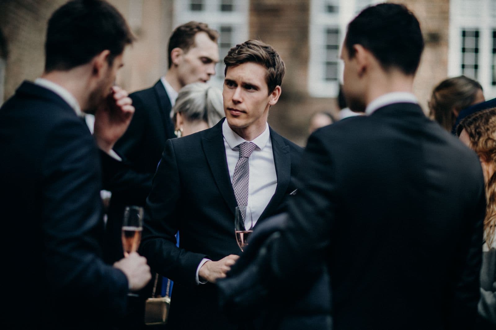 Een groep professionals staat samen te praten met een drankje in de hand tijdens een netwerkborrel