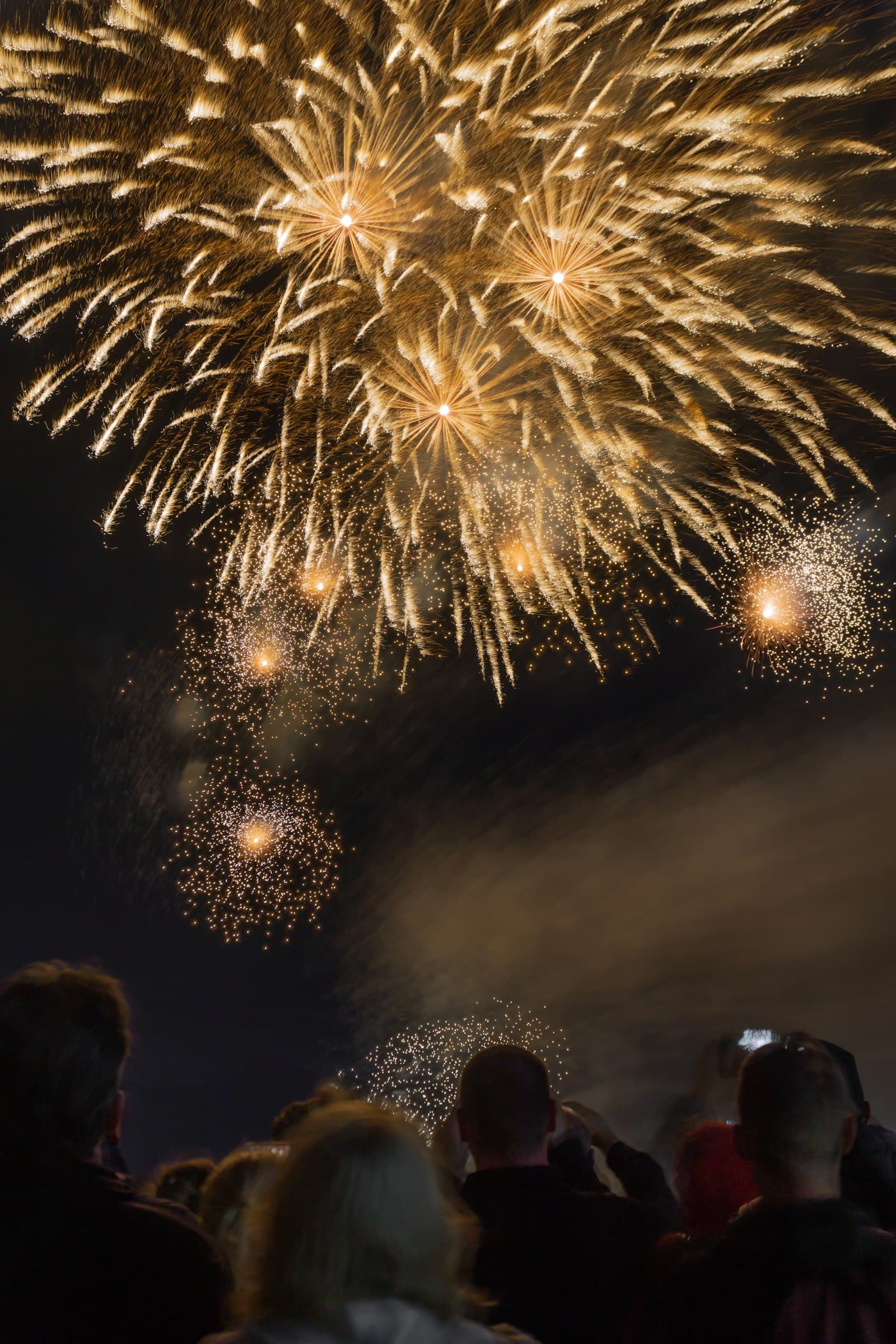 Mensen kijken samen omhoog naar gouden vuurwerk in de nacht van oud en nieuw, een warm beeld bij de jaarwisseling