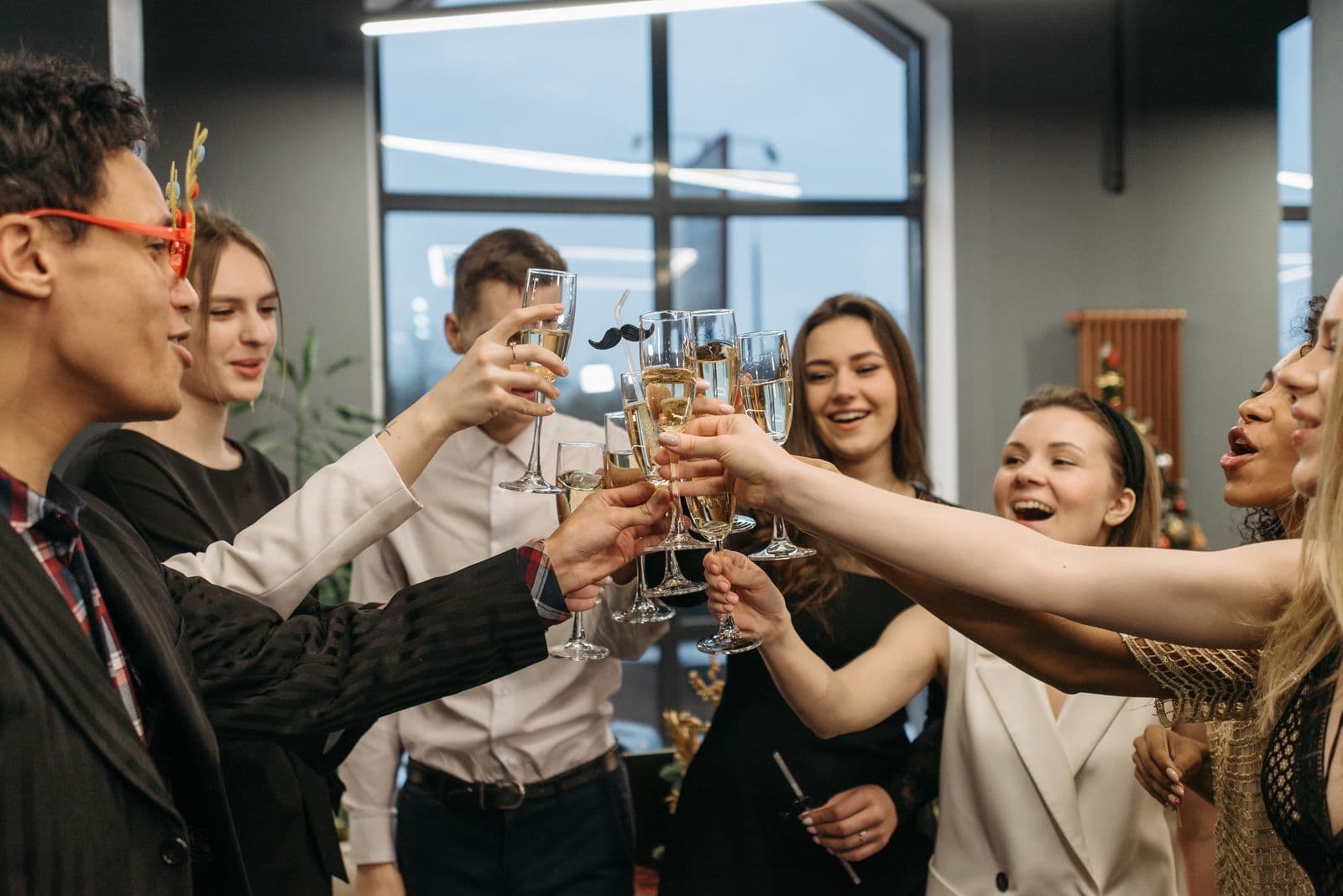 Een diverse groep collega's klinkt lachend met glazen tijdens een feestelijke borrel op kantoor