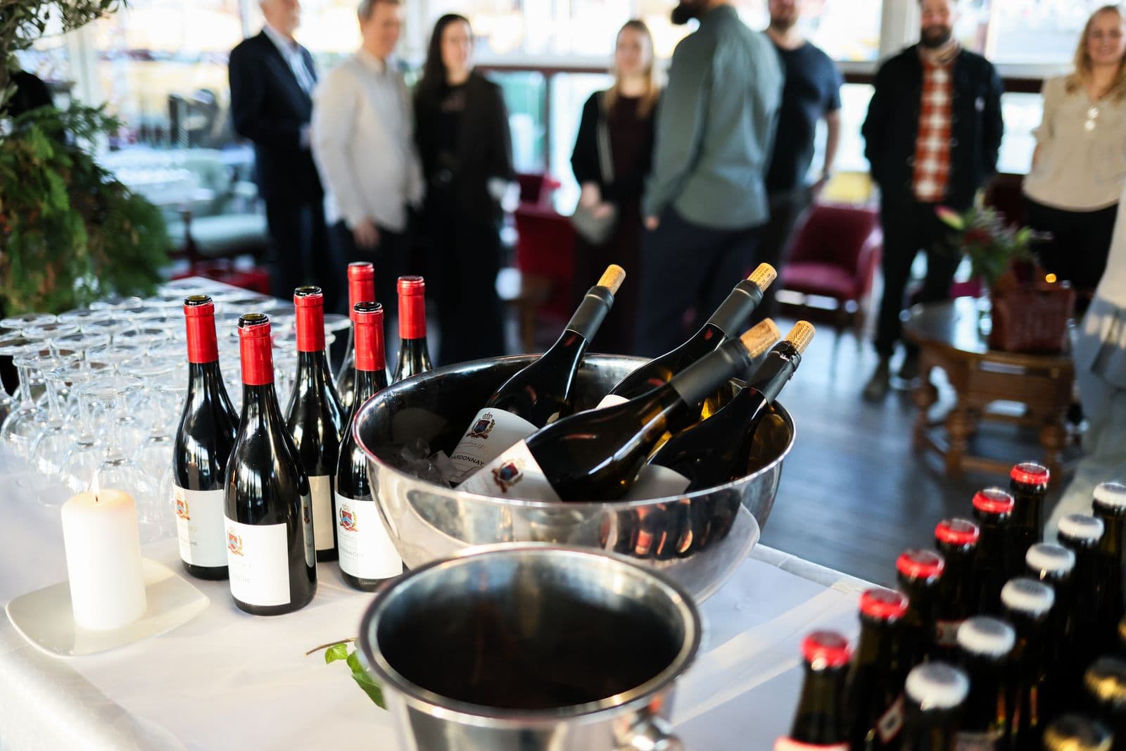 Gasten staan te praten rond een statafel met glazen en drankjes tijdens een zakelijke receptie