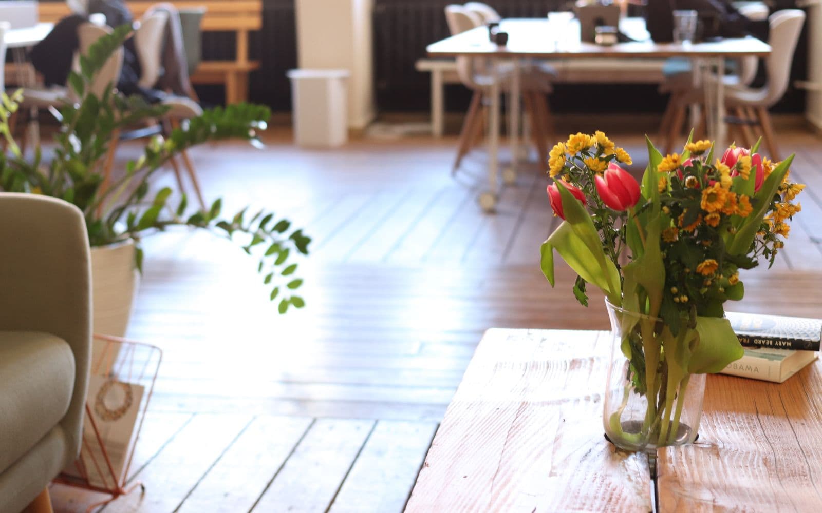 Een boeket verse tulpen en bloemen op een houten tafel in een licht, warm kantoor, passend bij een attent bedankje op Secretaressedag